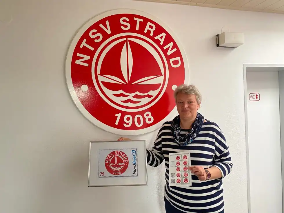 Bettina Ossyra, Geschäftsstellenleiterin beim NTSV Strand 08 präsentiert die eigene Briefmarke mit dem Vereinslogo des Timmendorfer Sportclubs.