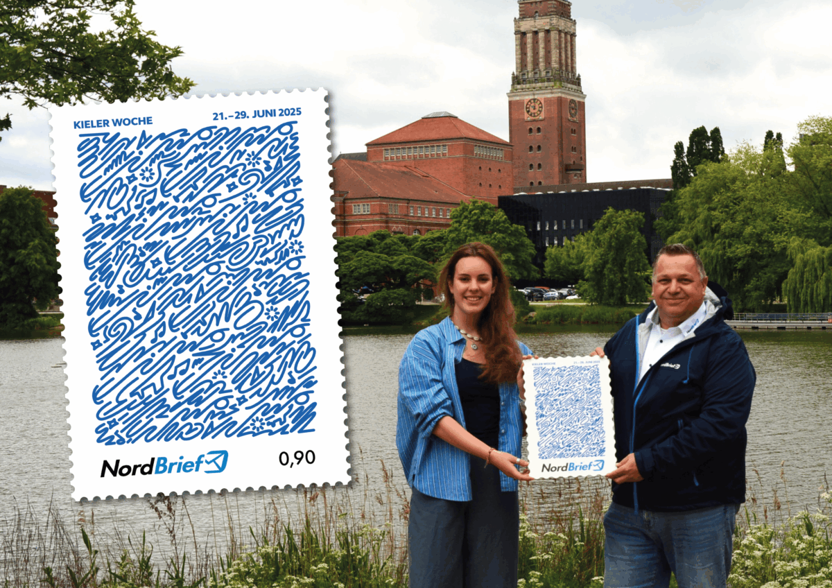 Zwei Personen präsentieren eine übergroße Briefmarke zur Kieler Woche 2025 mit blauem Musterdesign im Vordergrund des Kieler Rathauses
